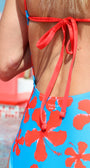 Blue swimsuit with red floral pattern and 'Tucca' branding.