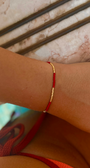 Red bracelet on a wrist styled with a Tucca Swim bikini