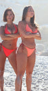 two women wearing reversible swimwear on a beach