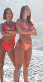 two women wearing reversible swimwear on a beach