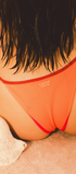 Person wearing an orange bikini with red straps on a beach.