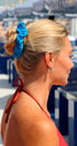 Woman with a blue scrunchie in her hair at an outdoor event